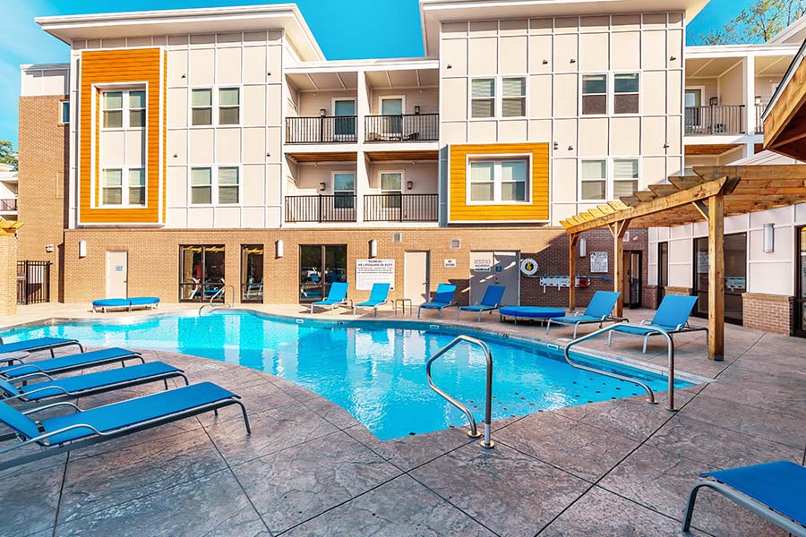 A bright blue pool and an exterior view of an apartment building at Echo Park Bloomington Apartments.