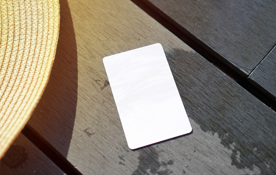 Summer hat and key card on a deck floor.