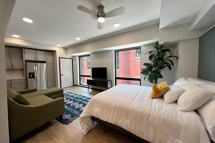 Even a fun studio apartment like this one at Block 20 needs some furniture to feel homey. View of a bed, couch, and kitchen in a studio apartment
