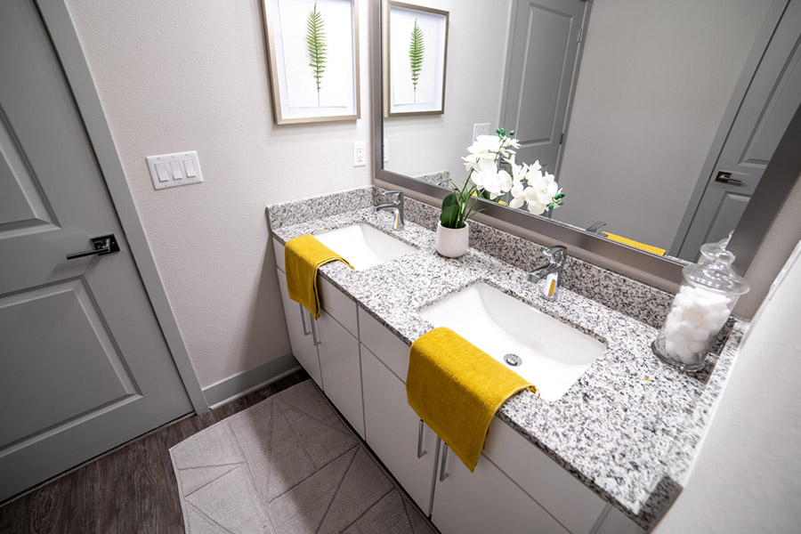 Black and gray countertop with a large mirror inside a bathroom. It is located at Verge Luxury Flats Apartments.